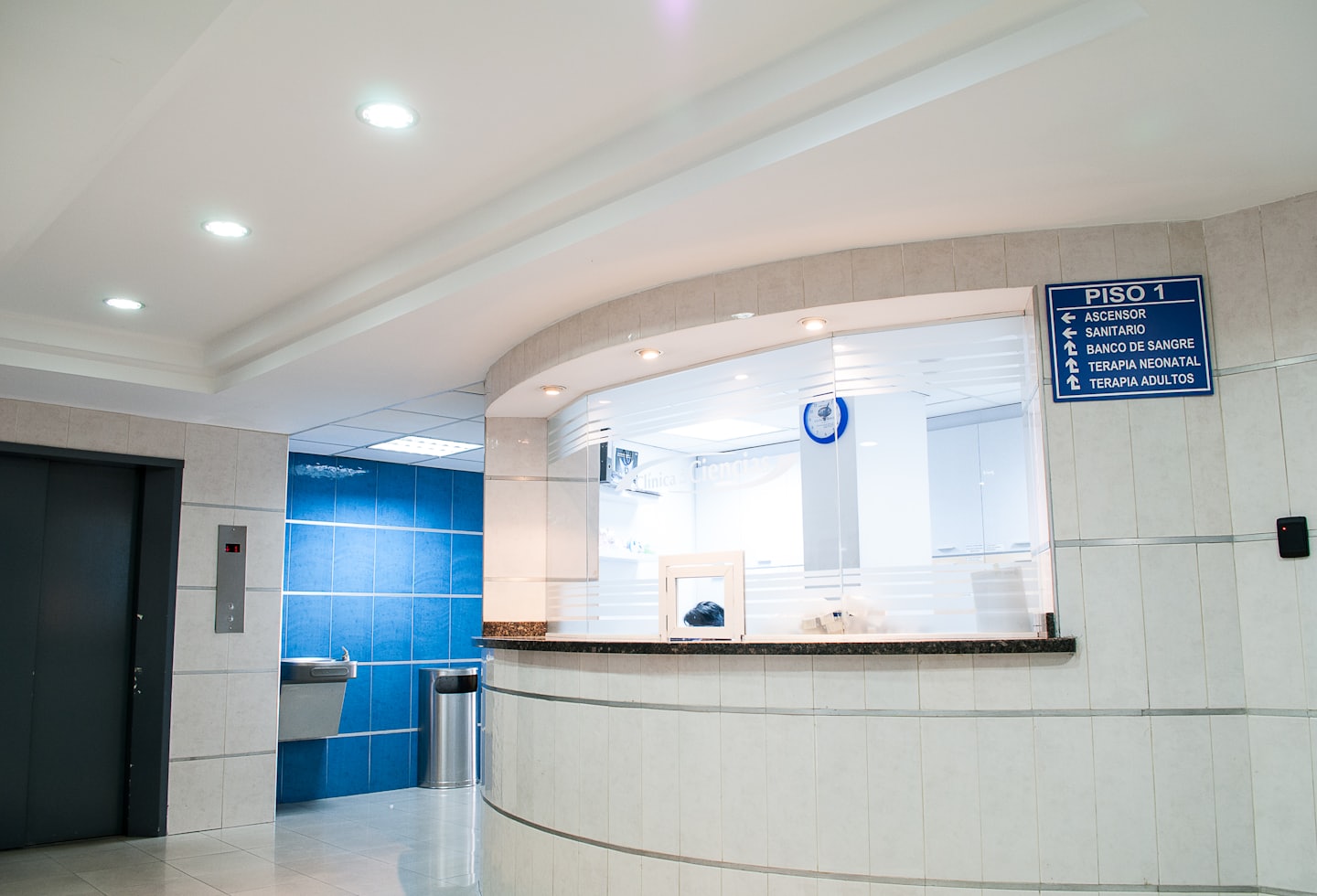Recepción moderna con escritorio curvo y azulejos azules.