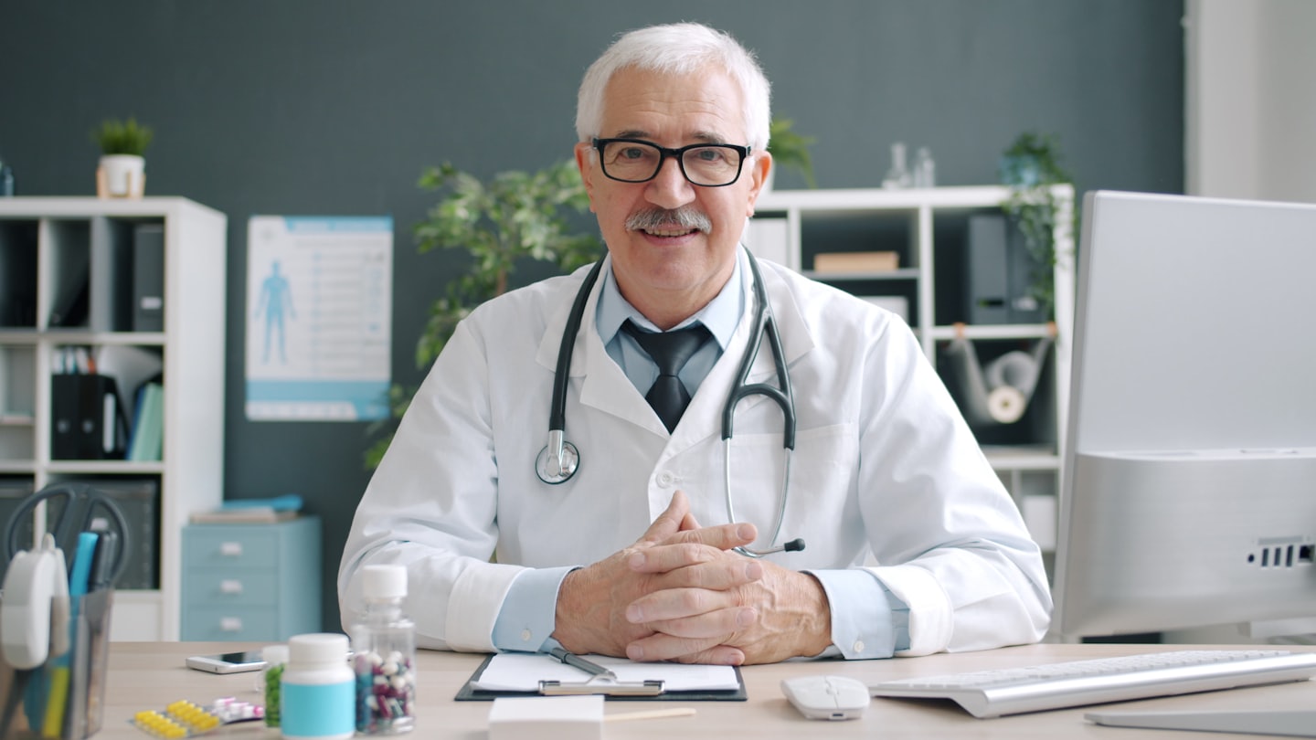Médico sentado en su escritorio en la consulta de una clínica.