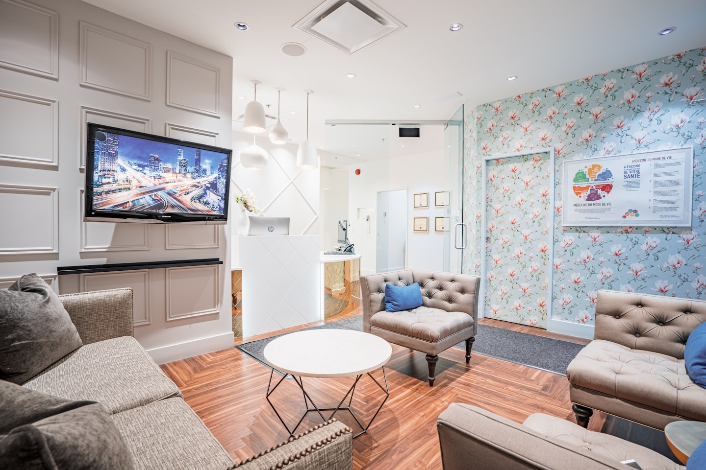 Sala de espera moderna con sofás, un escritorio de recepción y papel tapiz floral.
